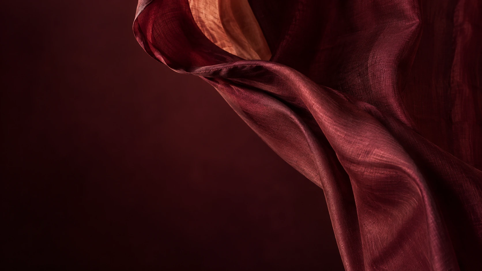 An editorial study of wine-coloured cloth, its fine folds catching warm light