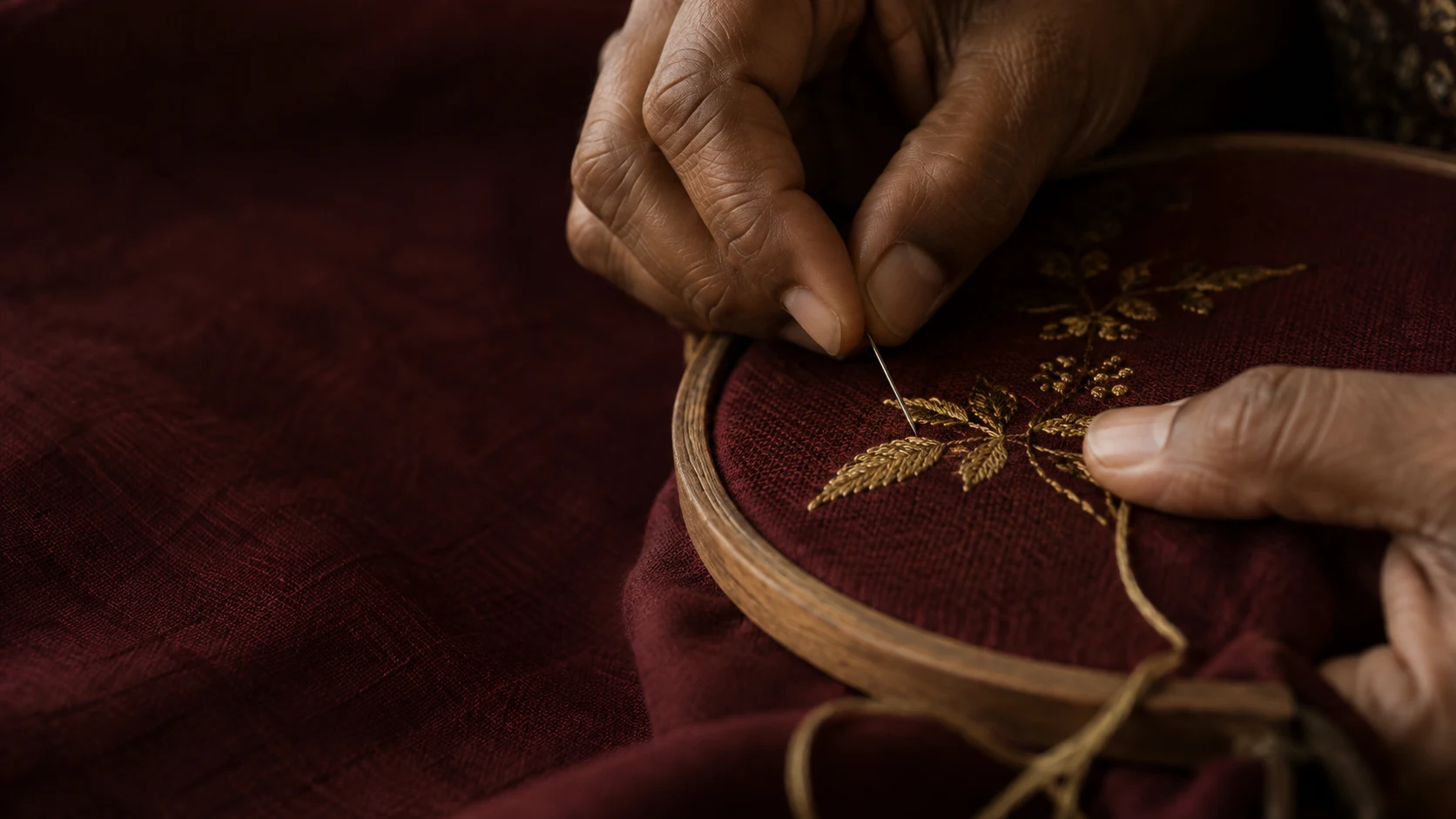 Gold thread is worked into wine-coloured cloth.