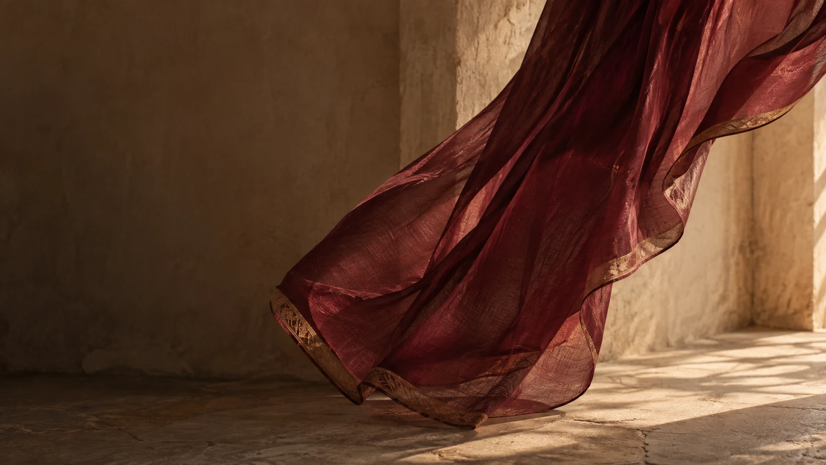 A fine wine-coloured hem moves through warm afternoon light.